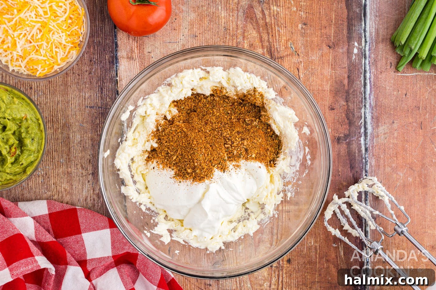 Cream cheese, sour cream, and taco seasoning being mixed in a bowl.