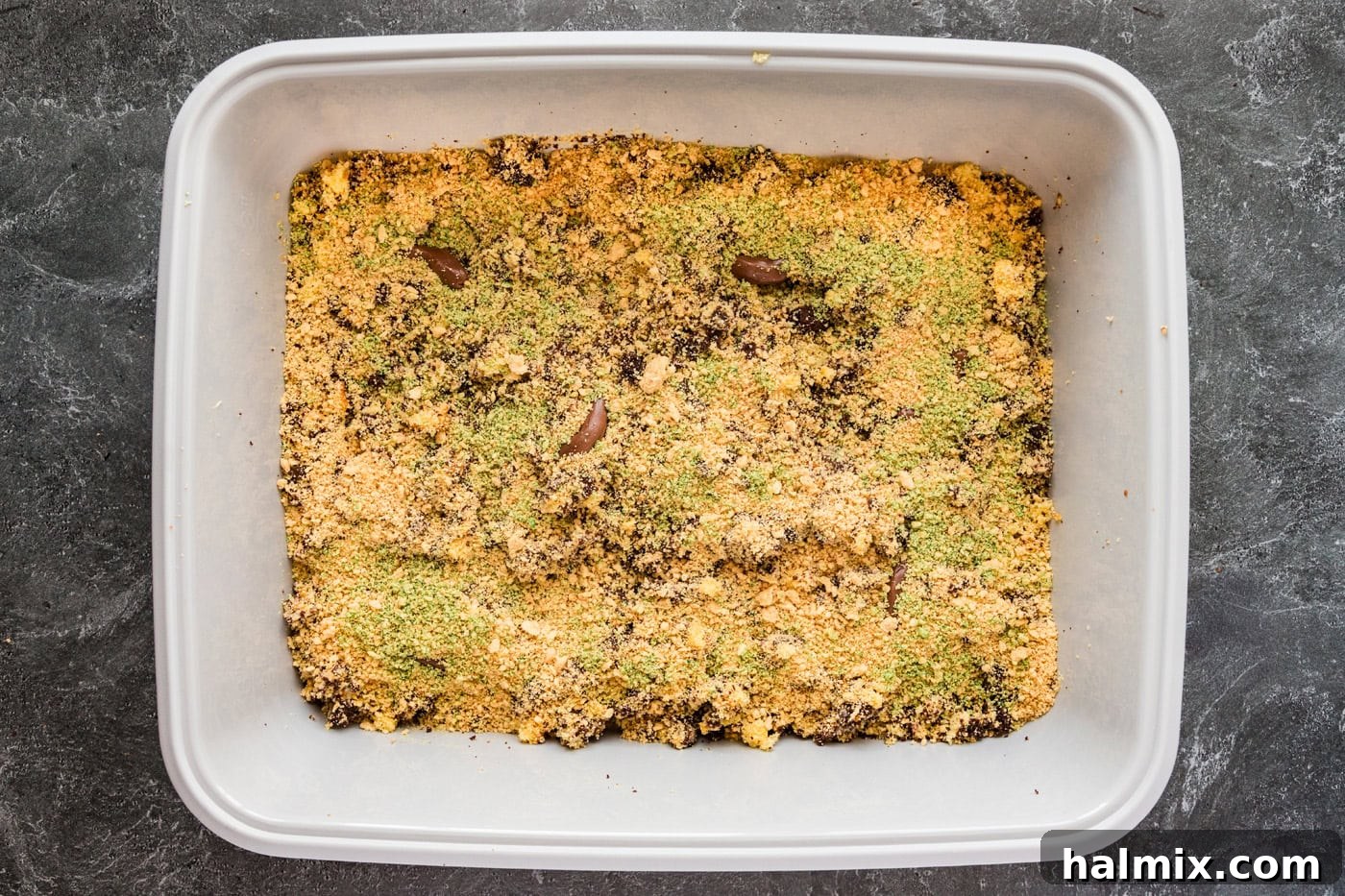 Green-tinted cookie crumbles lightly scattered on top of the kitty litter cake, adding to its realistic appearance.