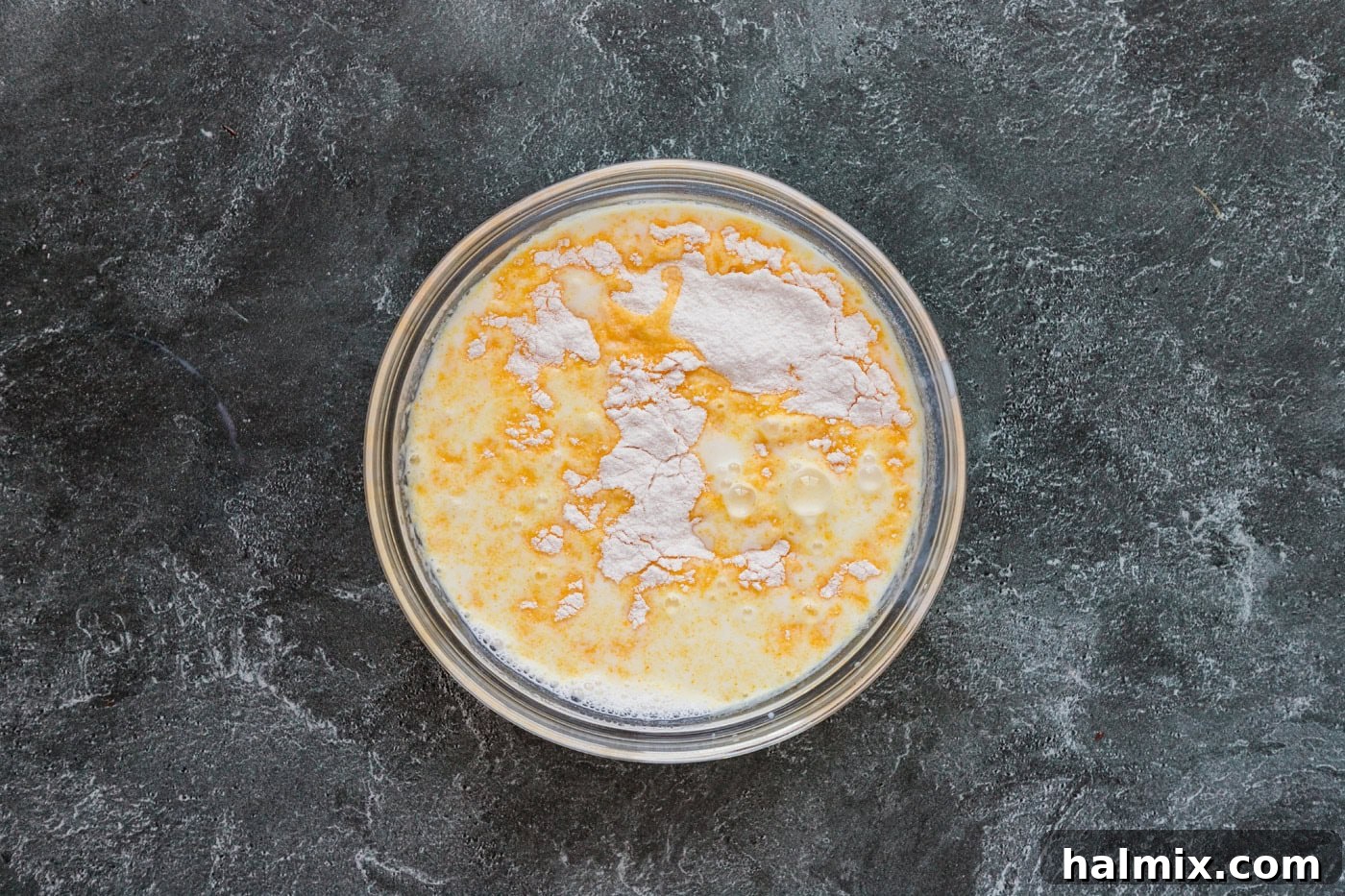 Instant pudding mix in a bowl with milk, being prepared and whisked until smooth.
