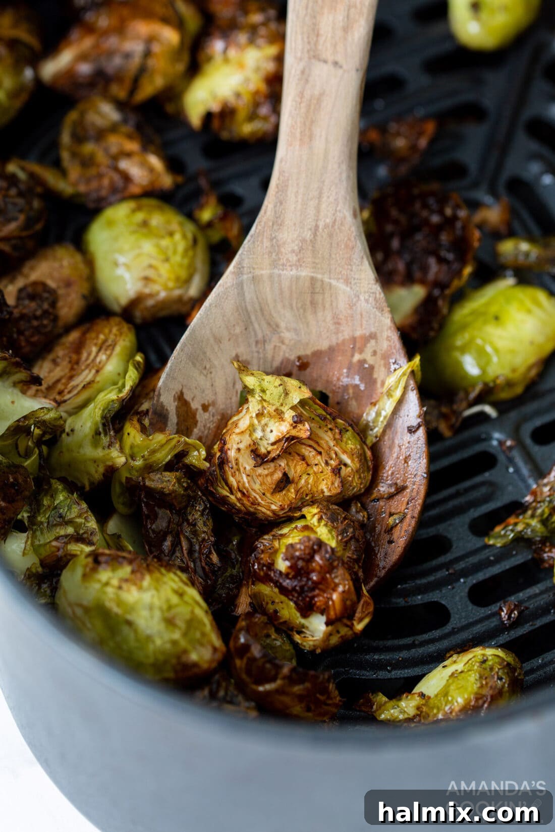 A spoon overflowing with golden-brown Air Fryer Brussels Sprouts, showcasing their crispy edges and tender texture.
