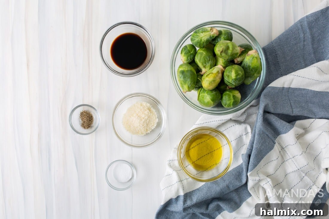 A flat lay of fresh Brussels sprouts, olive oil, balsamic vinegar, salt, pepper, and Parmesan cheese, laid out for the recipe.