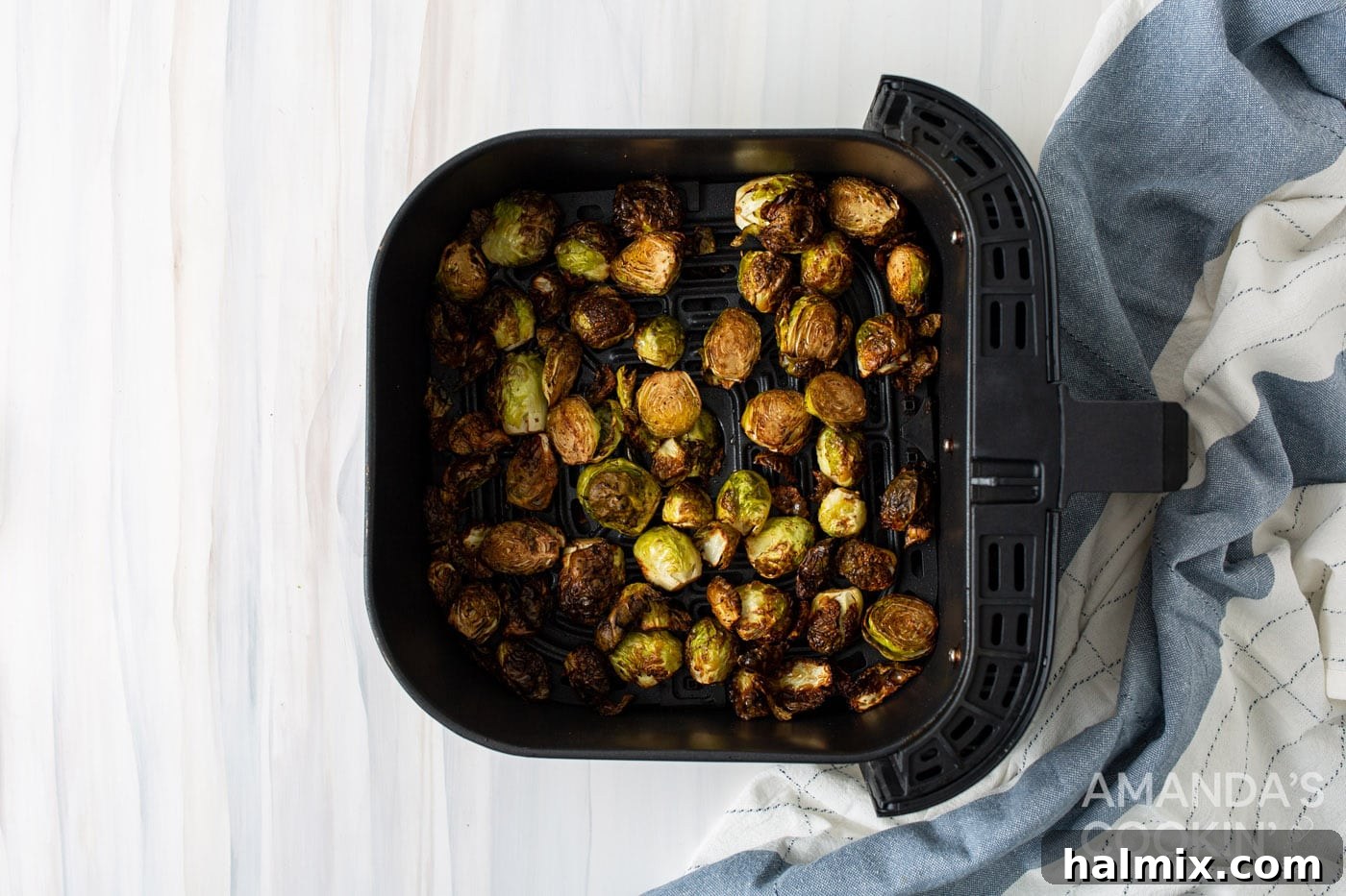 Close-up of roasted Brussels sprouts in the air fryer basket, dusted with Parmesan cheese.