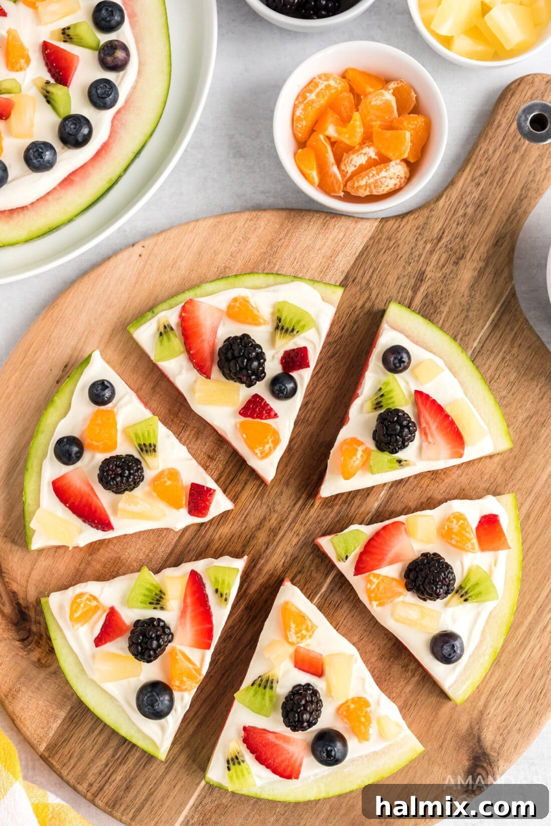 Crimson Crust Pizza 2 Watermelon Pizza on a cutting board, garnished with an array of fresh berries and kiwi
