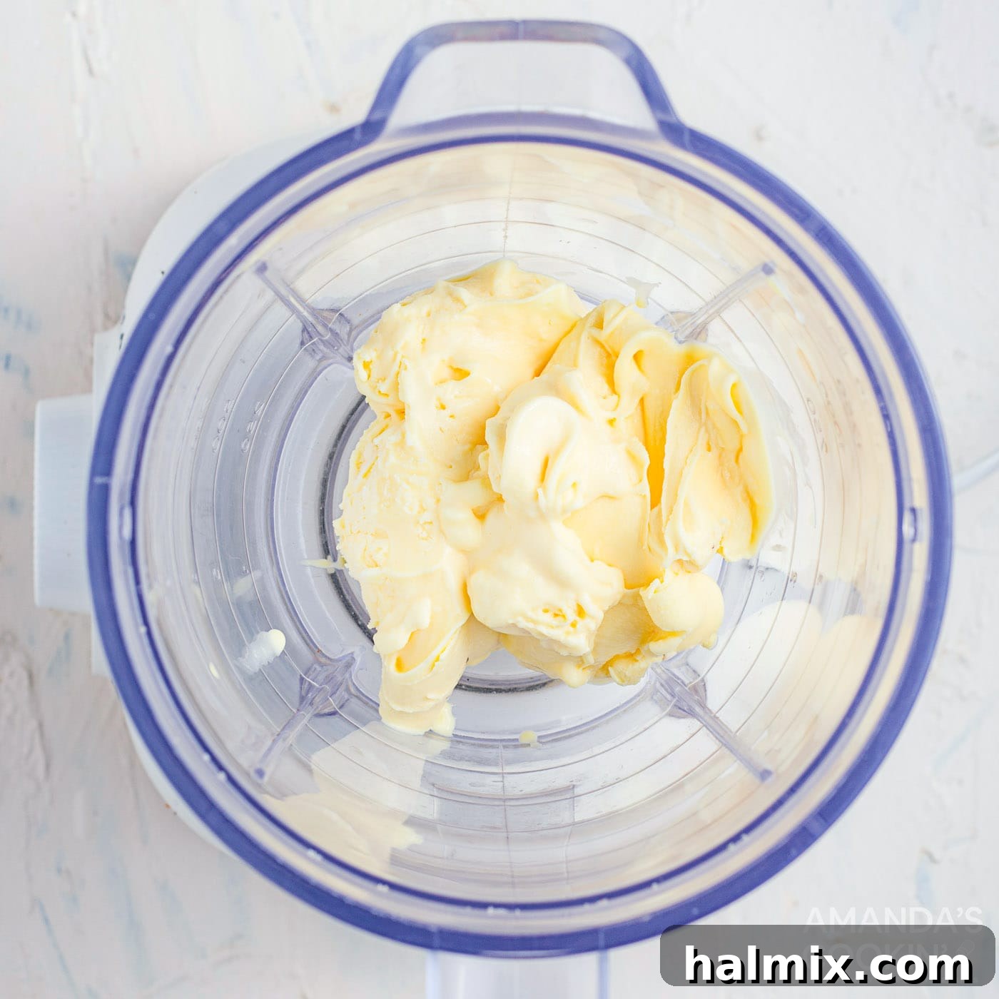 Ice cream, milk, and vanilla extract being blended in a high-speed blender for a smooth milkshake base