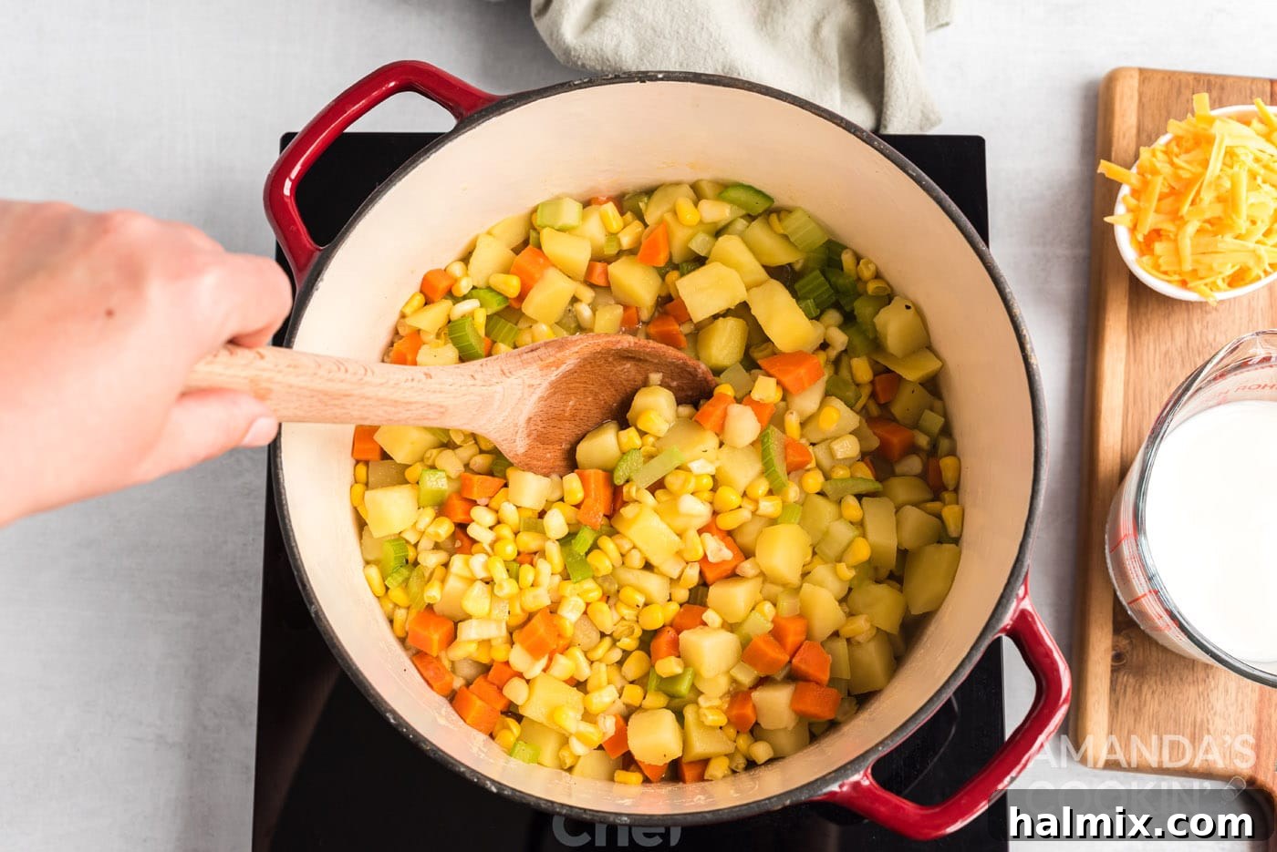 Sweet Corn Comfort 7 Frozen corn being stirred into the simmering vegetable and broth mixture in a pot