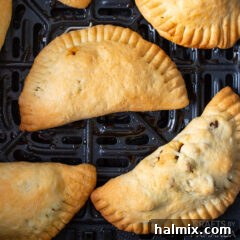 Golden brown empanadas resting in an air fryer basket after cooking.