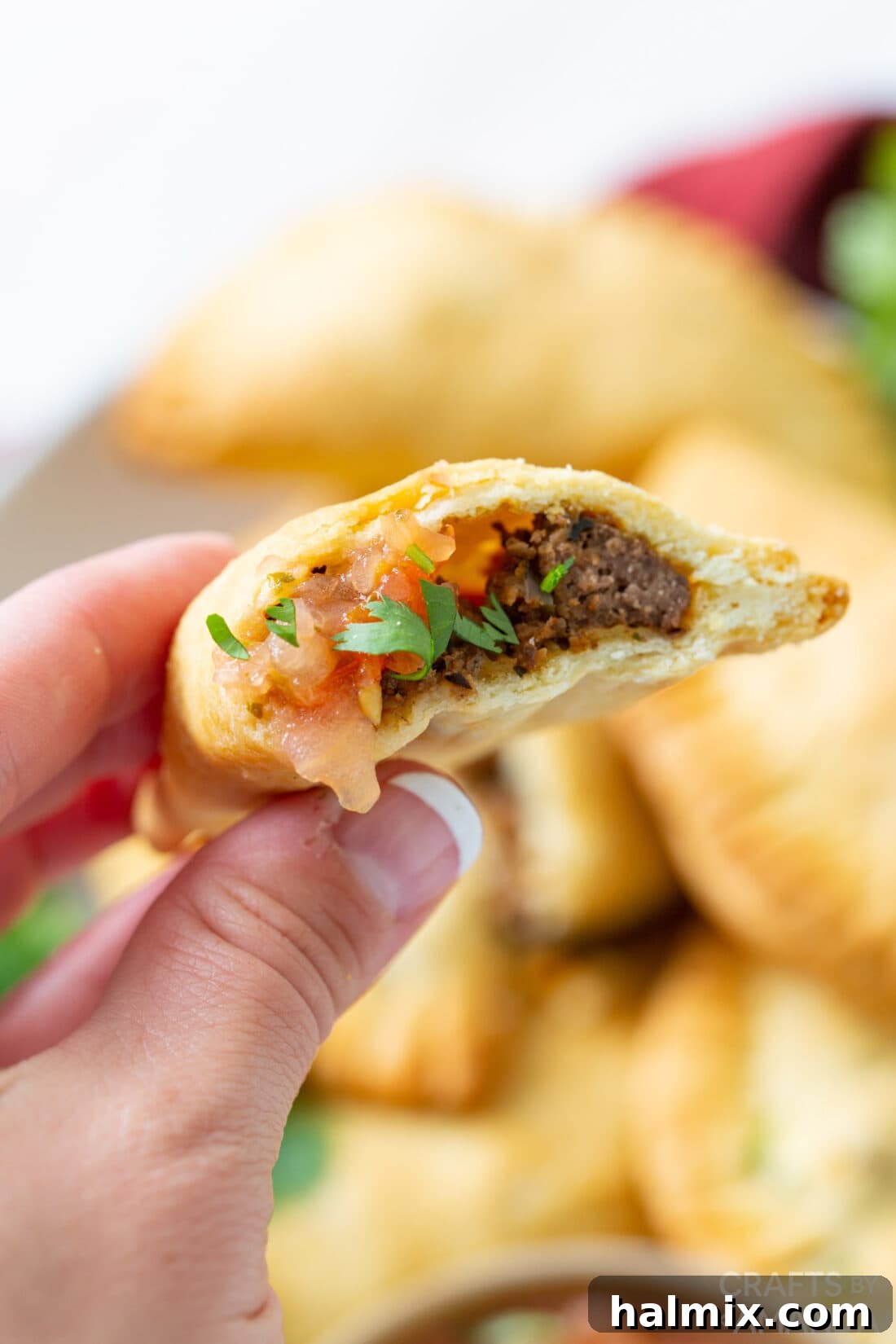 Close up shot of an air fryer empanada cut open, revealing the savory ground beef and vegetable filling.