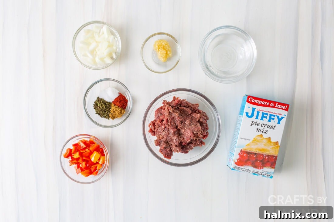 Ingredients laid out for air fryer empanadas including ground beef, diced peppers, onion, seasonings, and Jiffy pie crust mix.