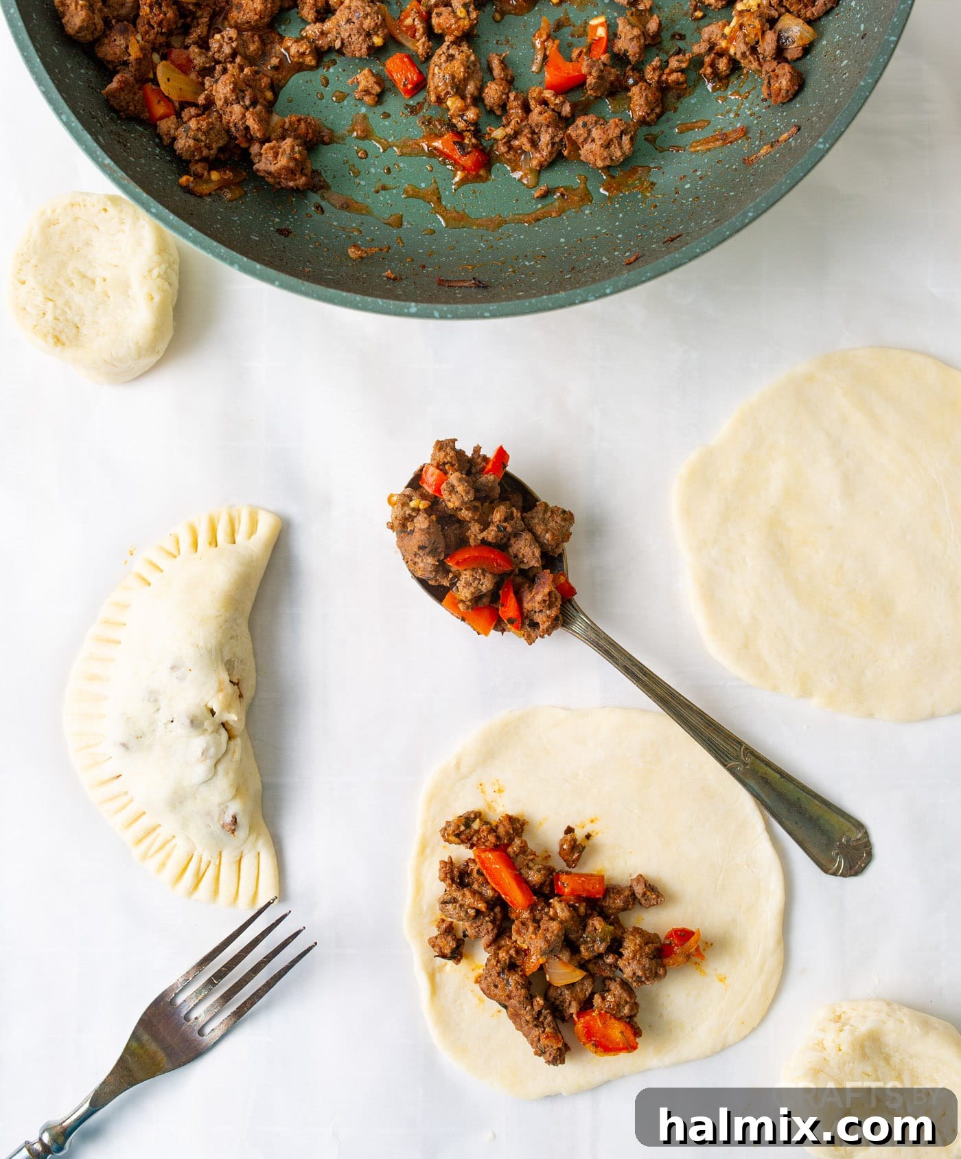 Process of filling pie dough discs with ground beef mixture and folding them.