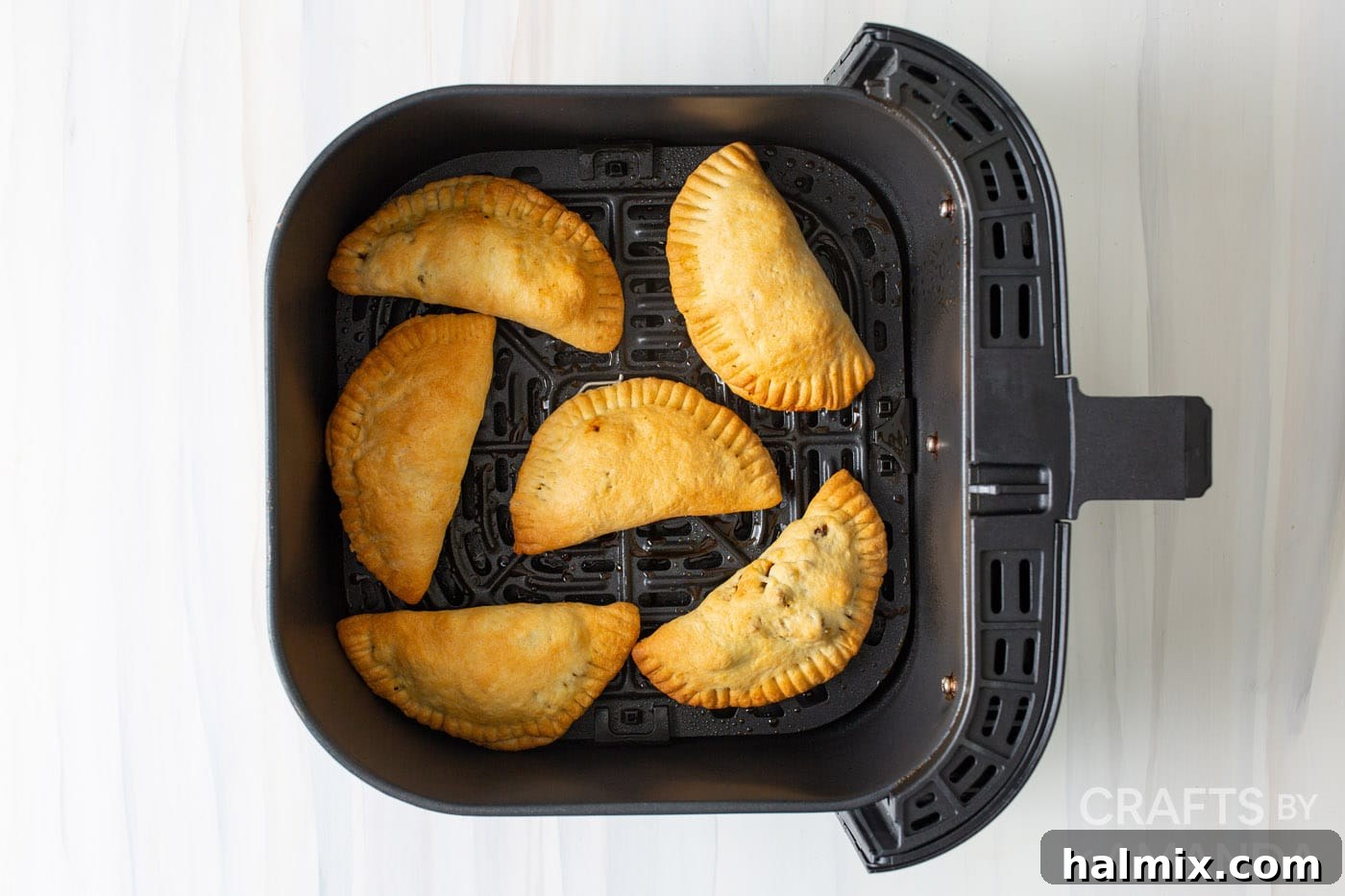 A plate of golden brown air fryer empanadas ready to be served, highlighting their appetizing appearance.