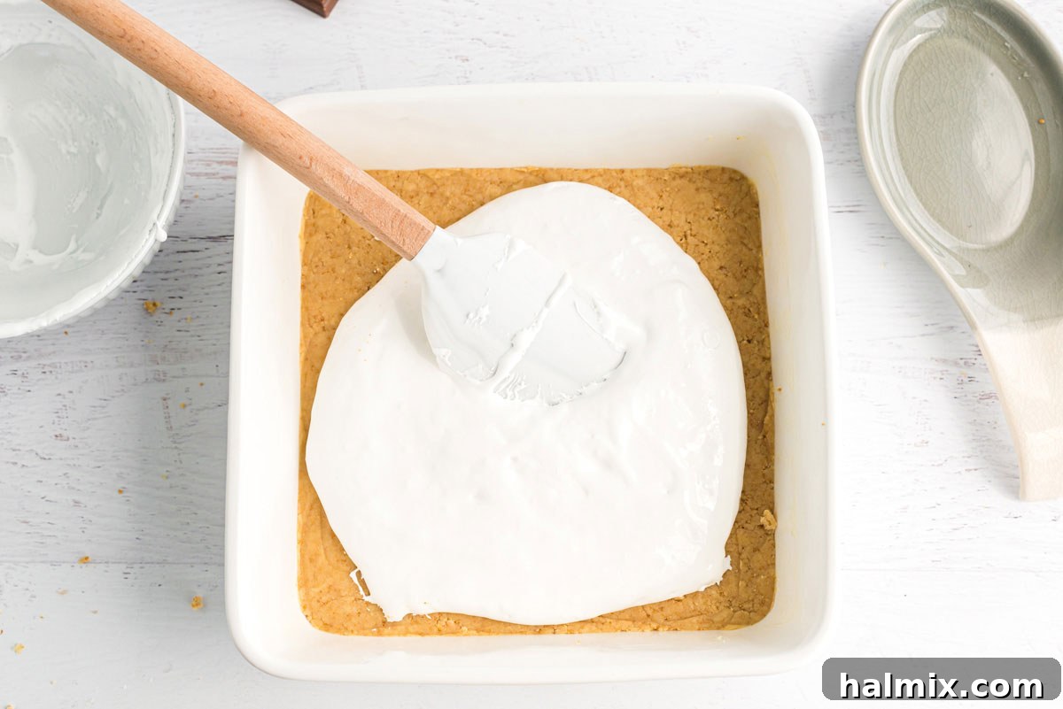 Gooey S'mores Bars 11 Spreading marshmallow creme over dough in pan