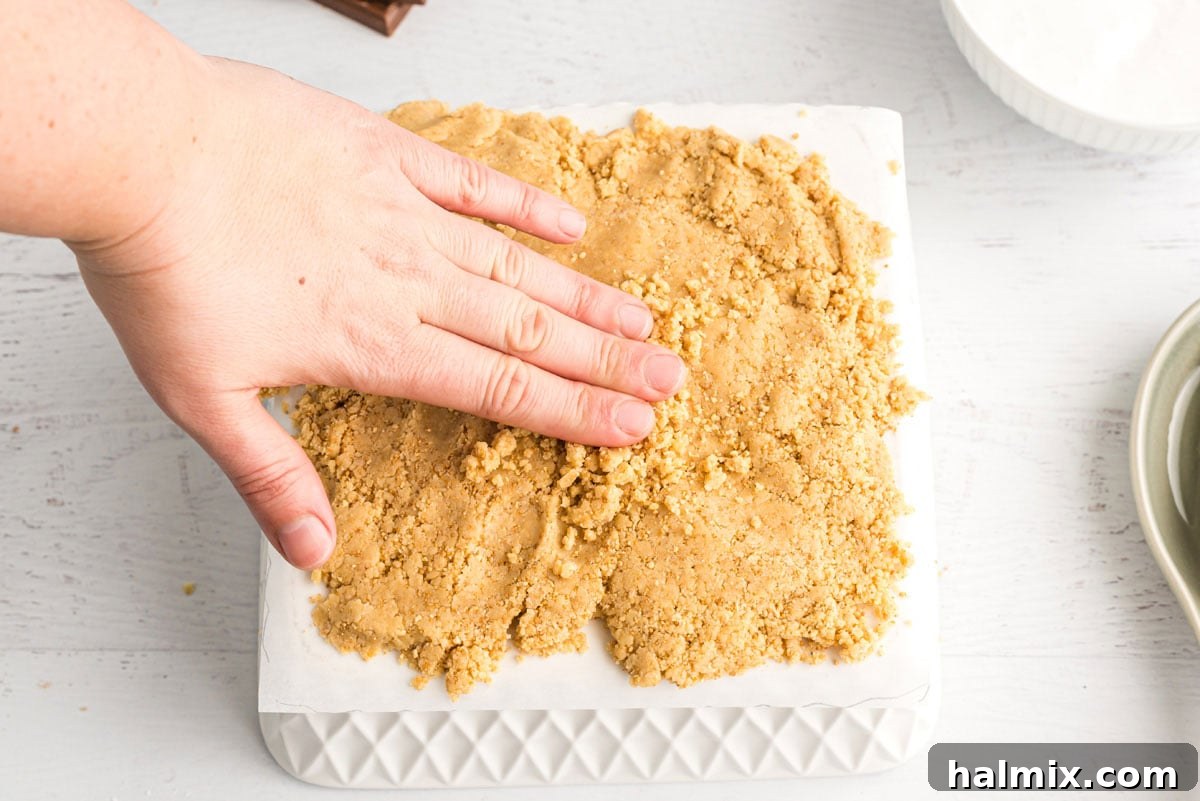 Gooey S'mores Bars 10 hand spreading dough on waxed paper