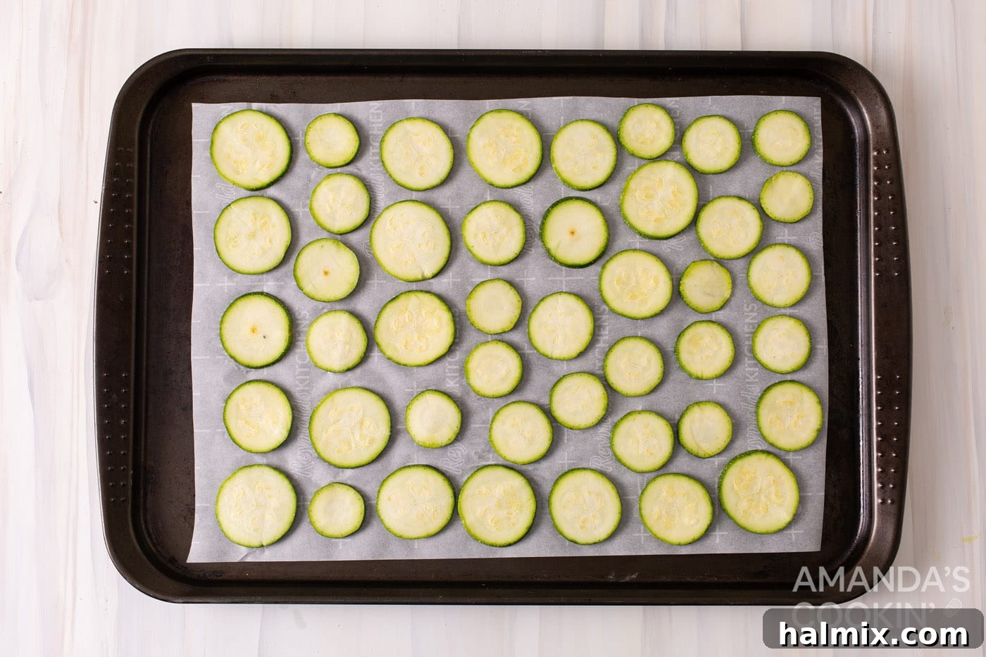 Sliced zucchini arranged on a sheet pan lined with parchment paper