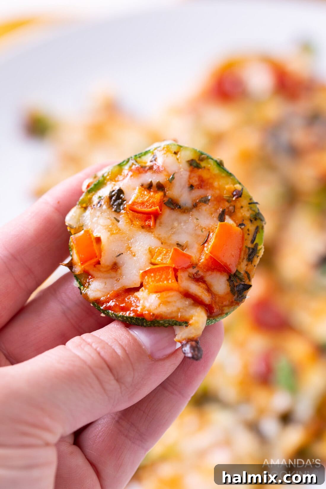 Hand holding a single Mini Zucchini Pizza Bite