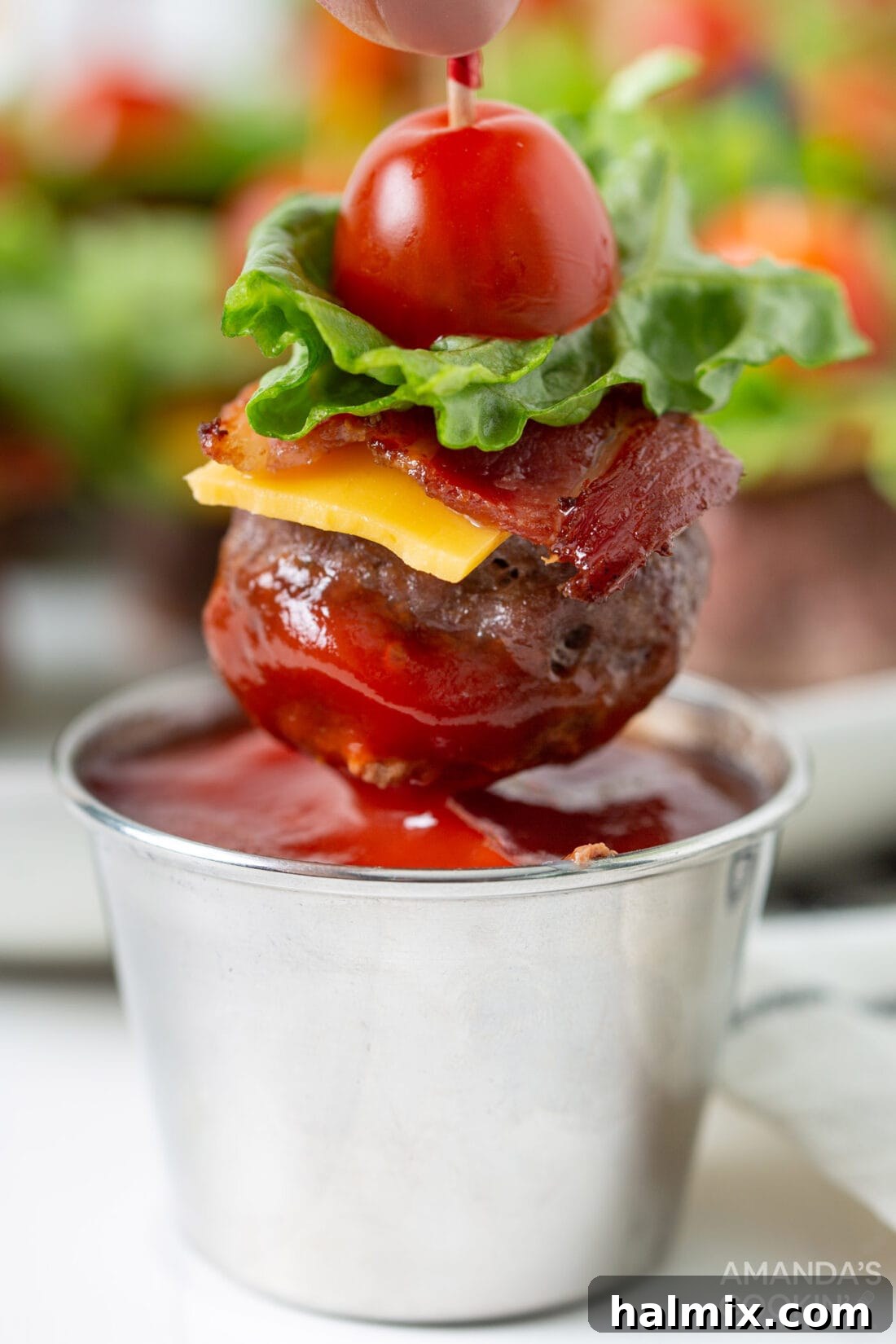 Bacon Cheeseburger Bombs 3 A Bacon Cheeseburger Meatball appetizer being dipped in ketchup, highlighting its saucy potential and delicious appeal.