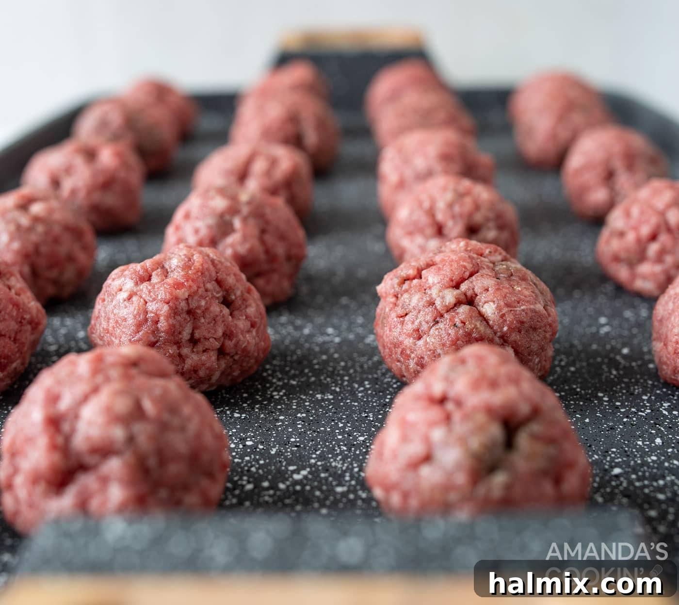 Bacon Cheeseburger Bombs 6 Uniformly shaped meatballs arranged neatly on a baking sheet, ready for the oven to bake to golden perfection.