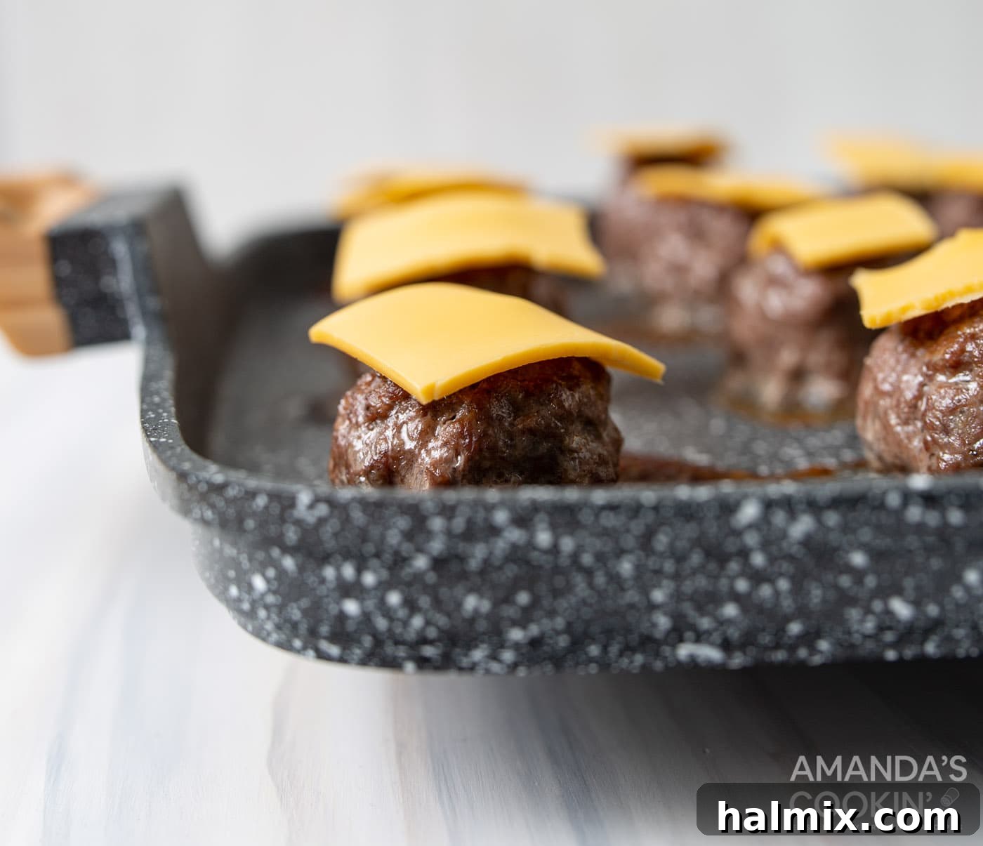 Bacon Cheeseburger Bombs 8 Miniature cheese slices carefully arranged on top of freshly baked meatballs, awaiting final assembly.