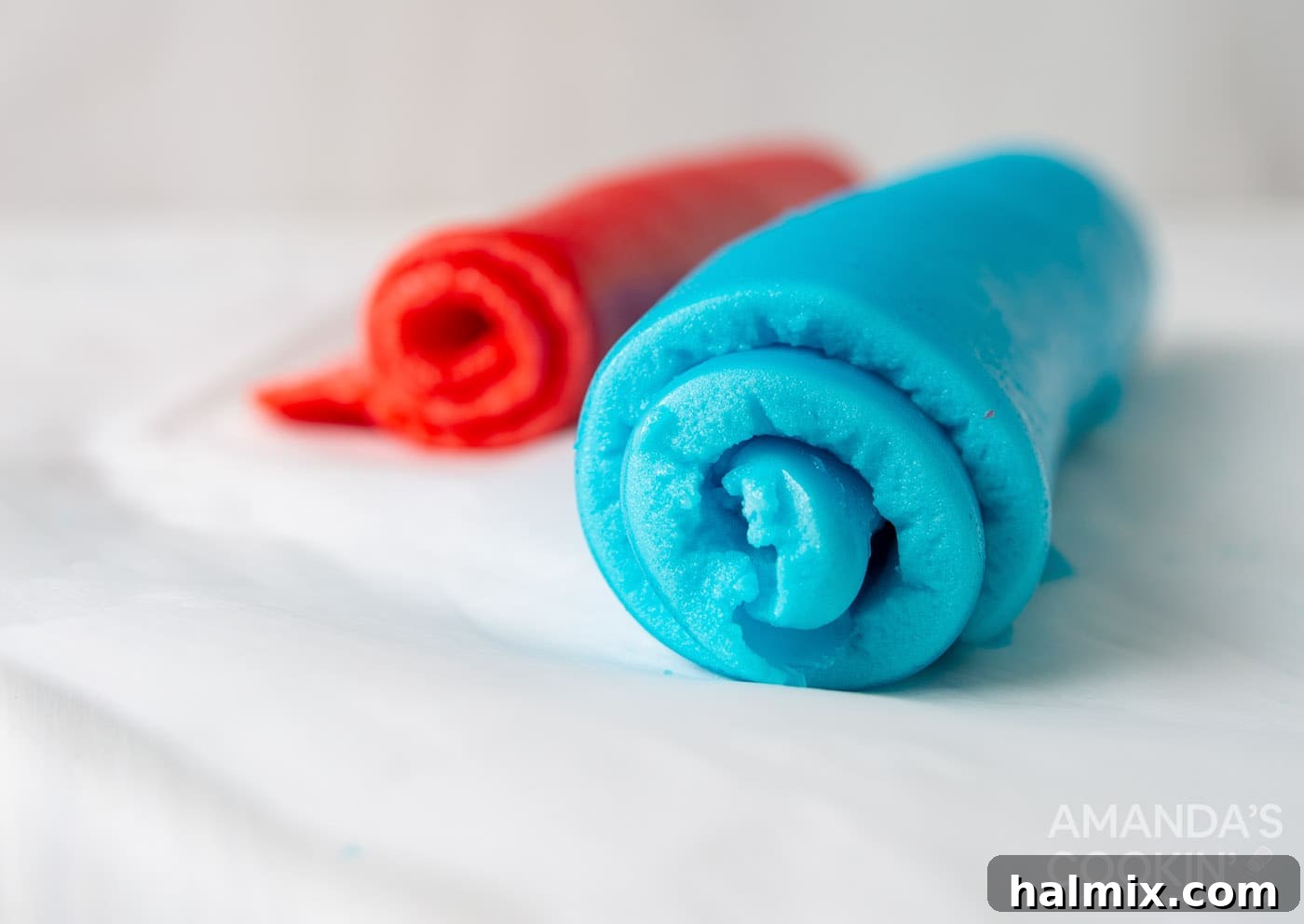 Finished Jello and marshmallow roll ups, cut into individual pieces and displayed on a white cutting board, showing their spiral pattern.
