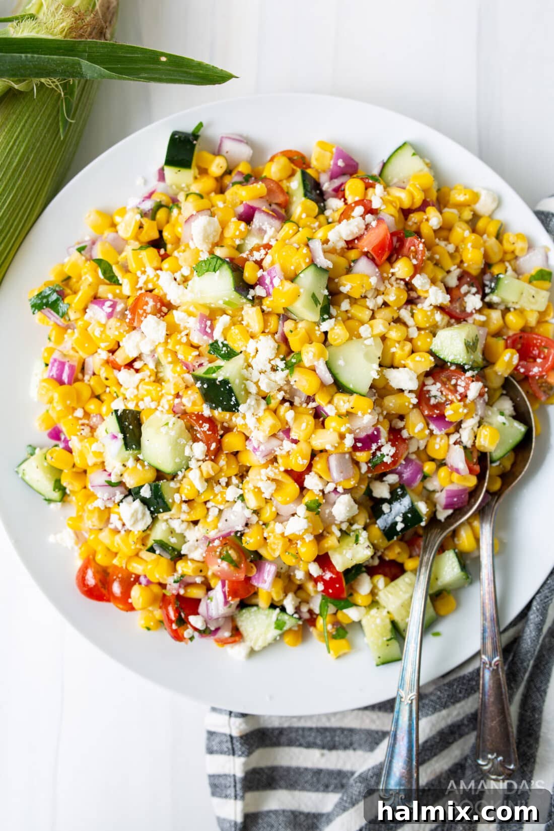 Sunshine Corn Salad 2 A vibrant plate of refreshing corn salad, showcasing sweet corn, crisp cucumber, red onion, juicy cherry tomatoes, and crumbled feta cheese, garnished with fresh herbs.