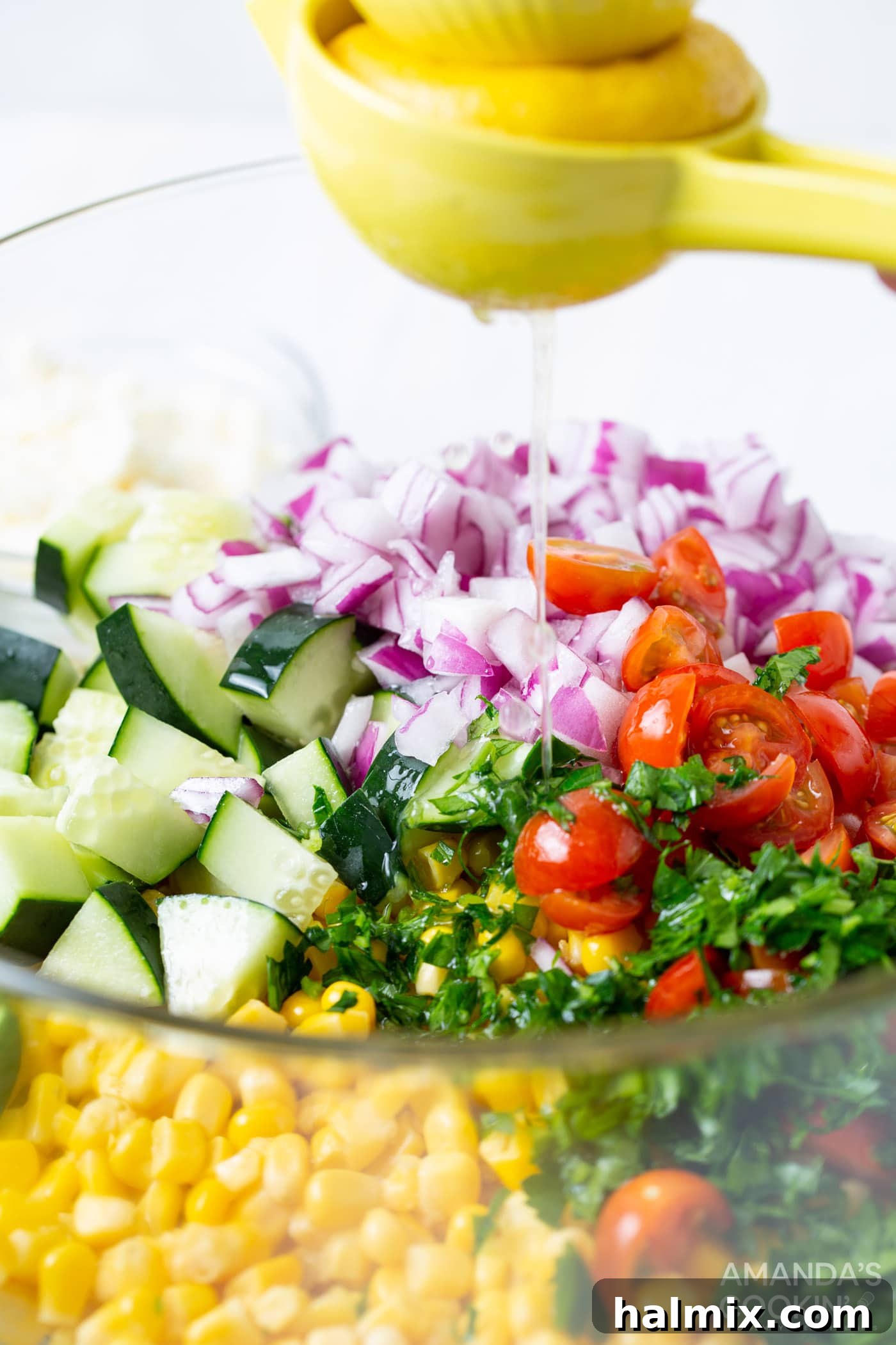 Fresh lemon juice being squeezed directly onto a vibrant corn salad in a mixing bowl, adding a bright and zesty flavor to the fresh vegetables.