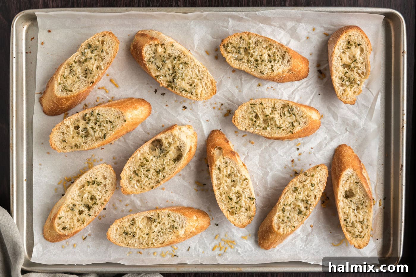 toasted bruschetta bread on a baking sheet with parmesan cheese