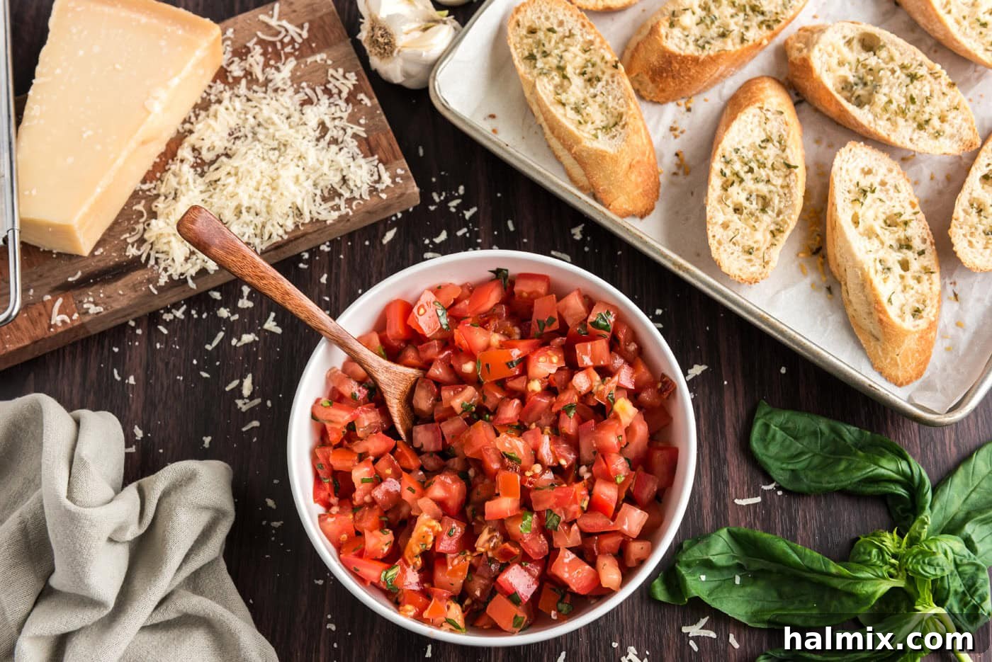 bruschetta tomato mixture in a bowl next to sliced bread with parmesan cheese