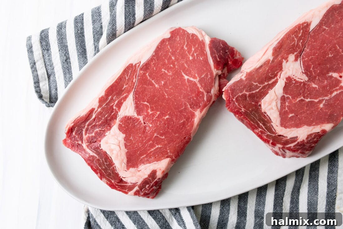 Key ingredients for grilling steak, including high-quality New York Strip cuts, coarse salt, freshly ground pepper, and butter