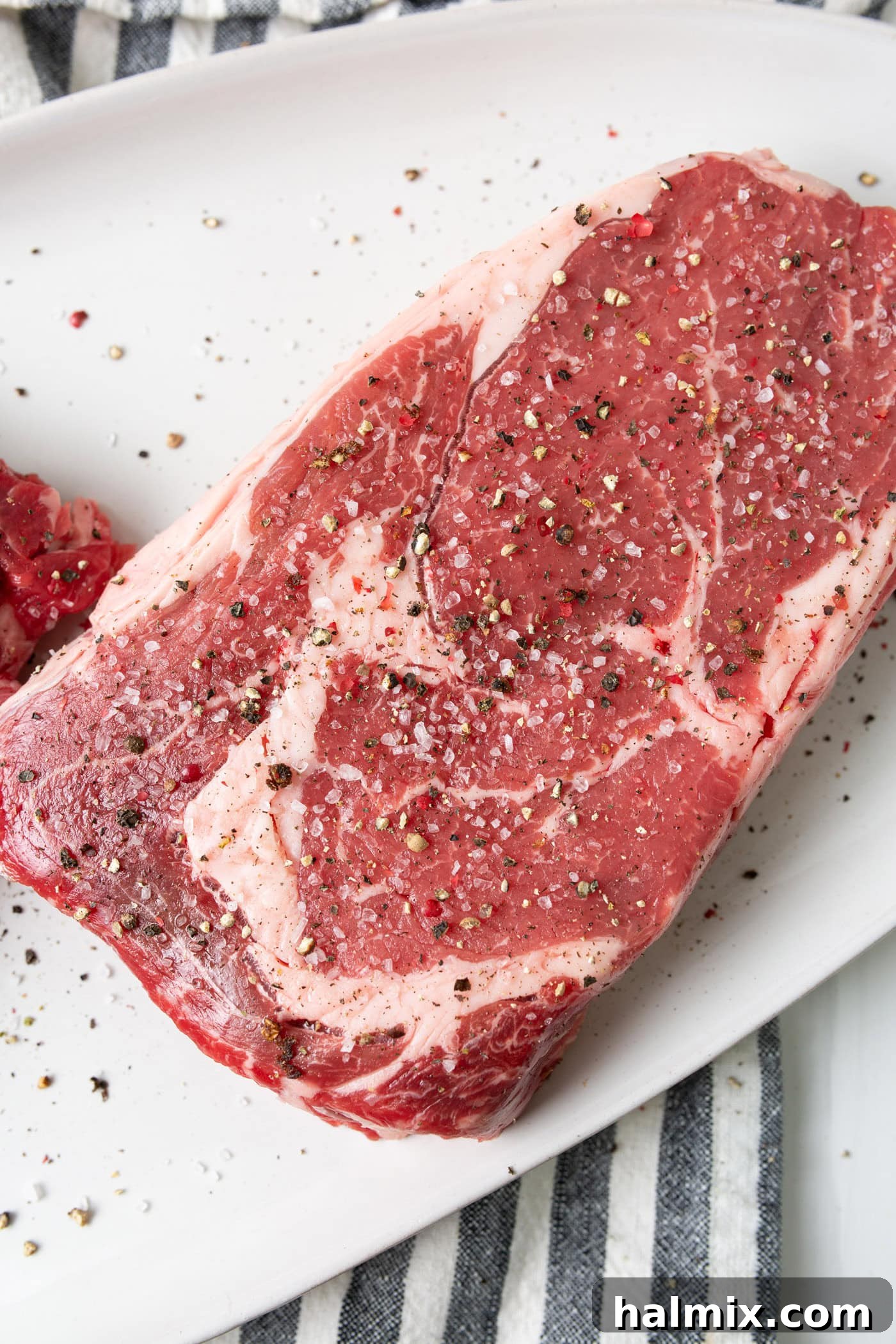 Steak generously seasoned with coarse salt and freshly ground black pepper, ready for grilling