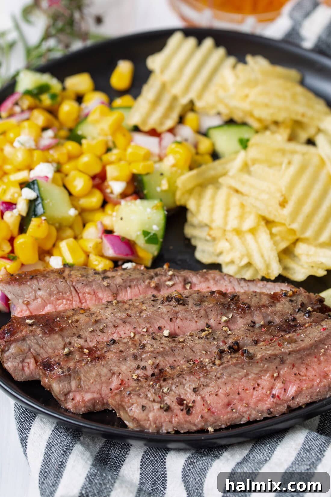 Grilled New York Strip Steak served on a plate with fresh corn on the cob, a perfect summer meal