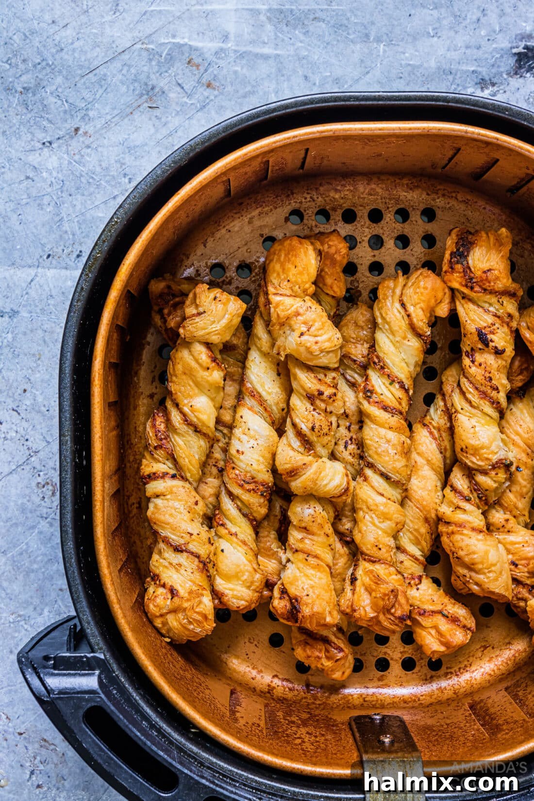 Several golden bread twists nestled in an air fryer basket
