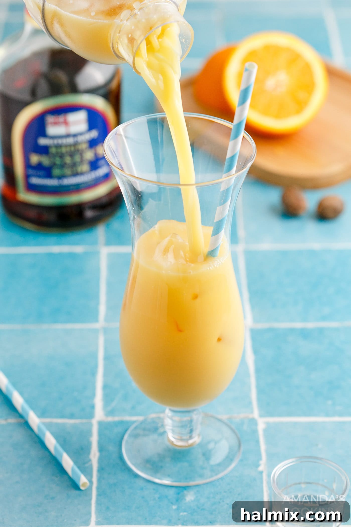 Pouring the strained Painkiller Cocktail into a hurricane glass filled with fresh ice