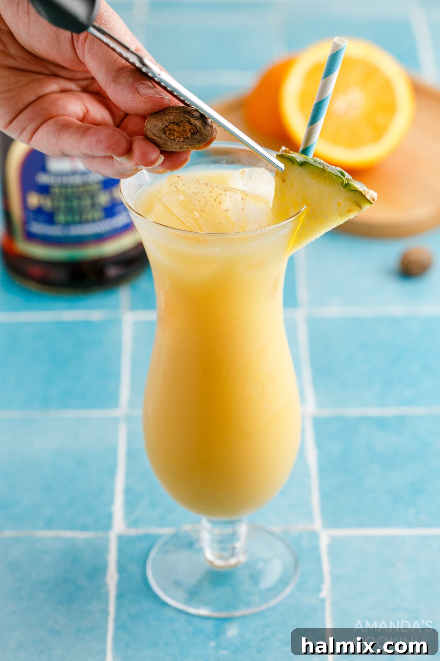 Adding a pineapple wedge garnish and freshly grated nutmeg to a Painkiller Cocktail
