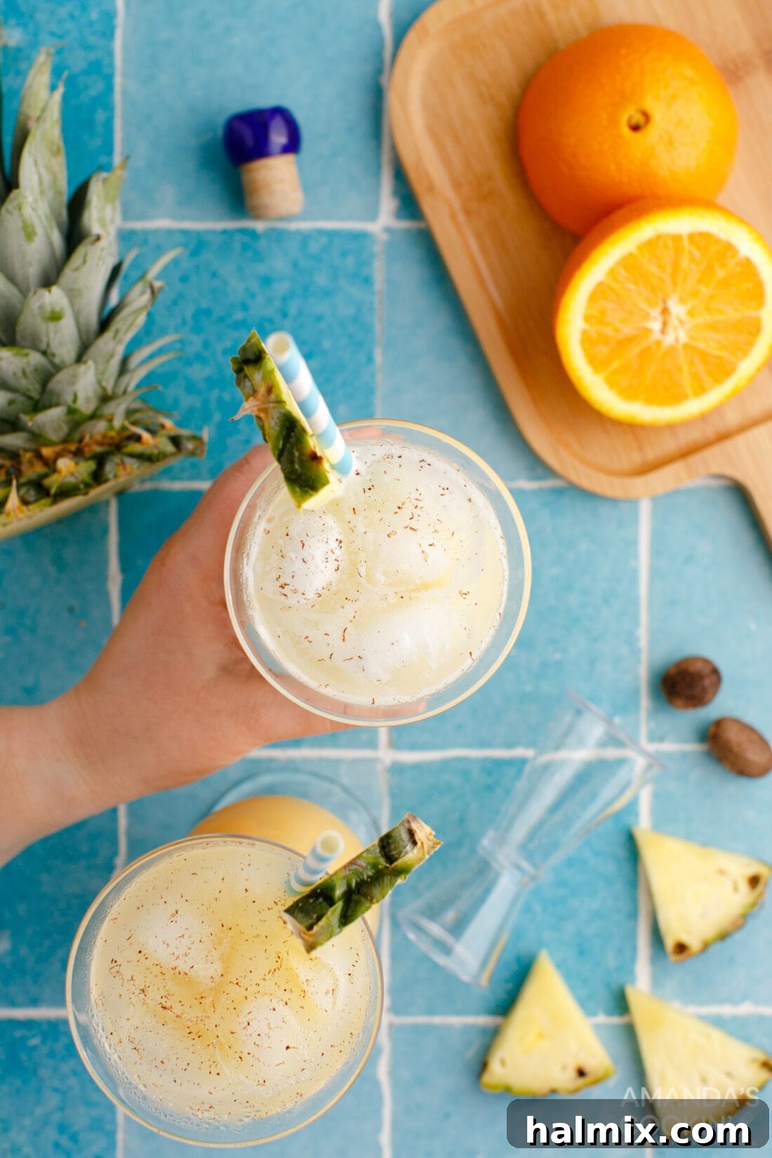 Hand reaching for a Painkiller Cocktail garnished with pineapple, emphasizing its refreshing appeal