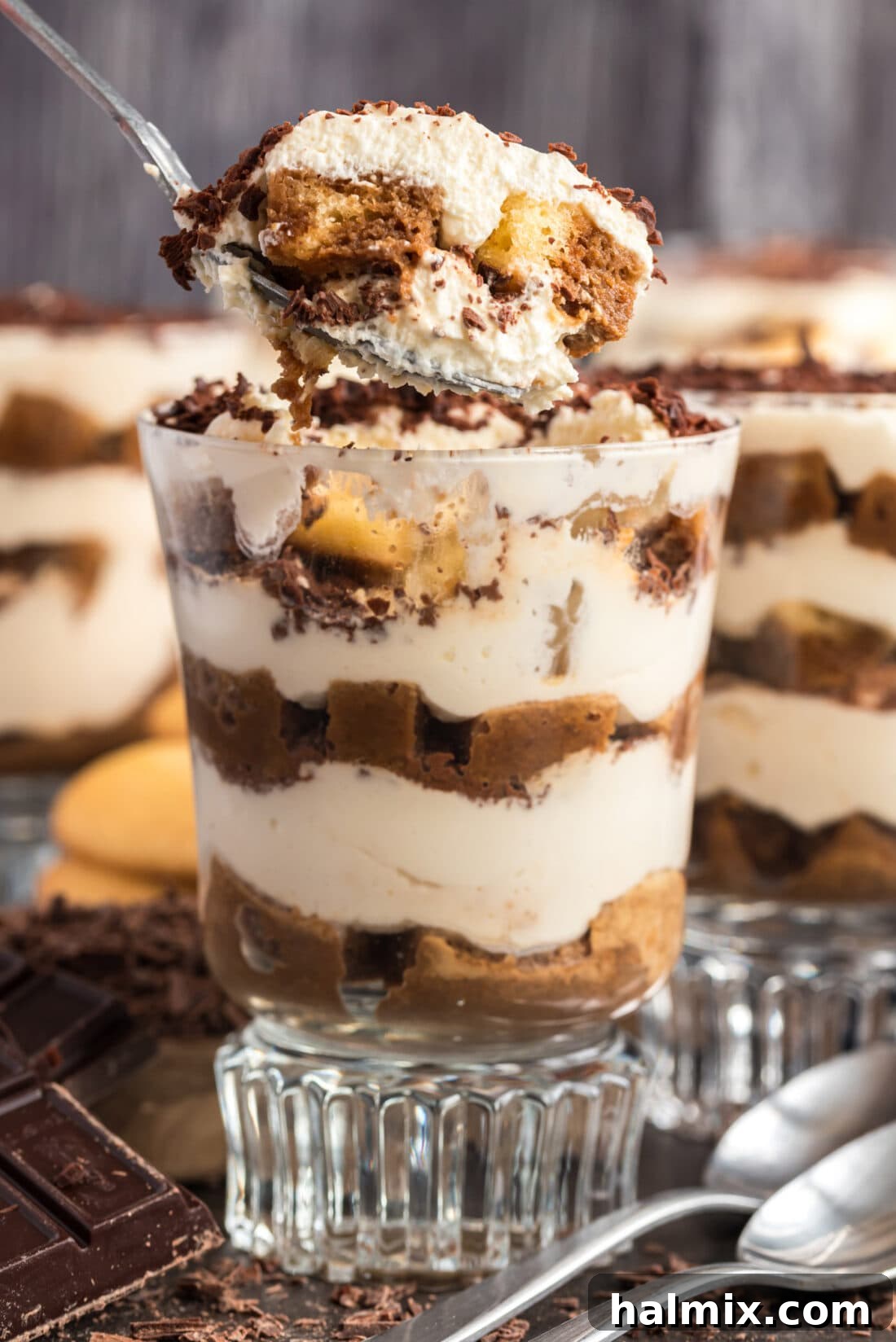 A spoonful of Bailey's Tiramisu Parfait being lifted out of a clear parfait cup, revealing the layers of ladyfingers, creamy filling, and espresso.