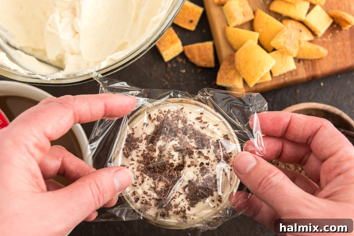 Individual Bailey's tiramisu parfaits being covered with plastic wrap, ready for chilling in the refrigerator.