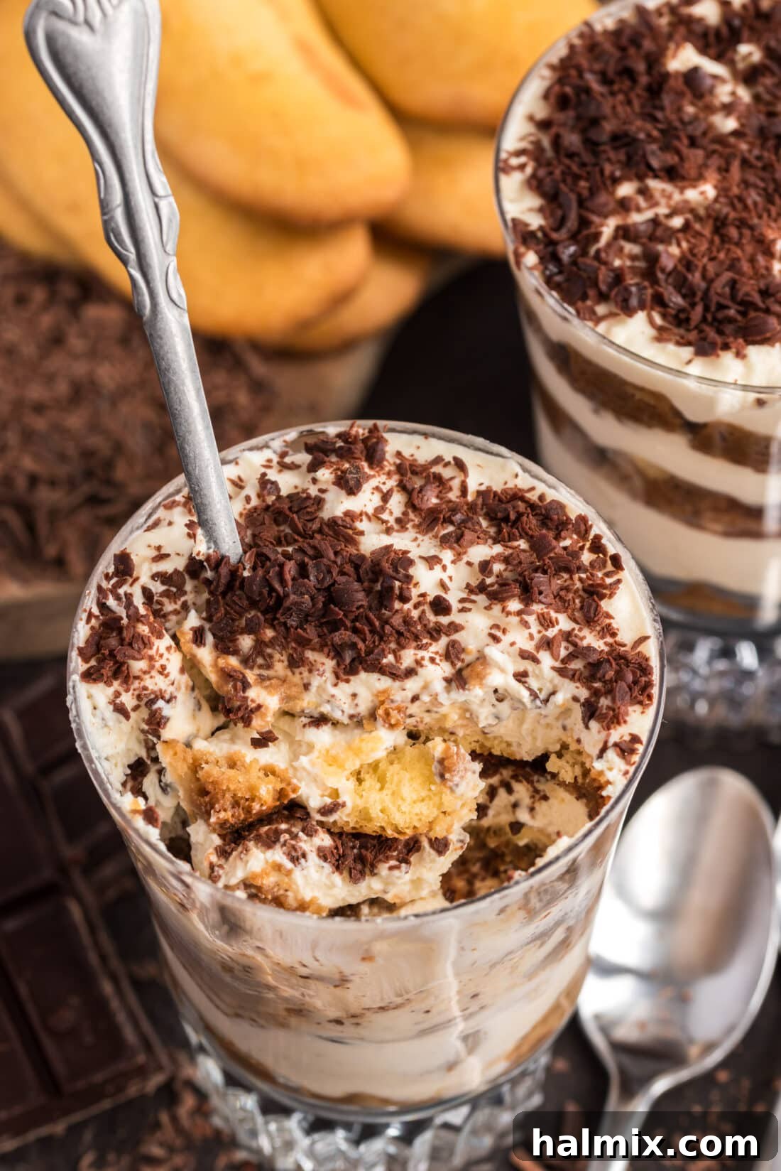 A spoon inserted into a Bailey's Tiramisu Parfait, revealing a perfect bite with all the creamy layers and espresso-soaked ladyfingers.