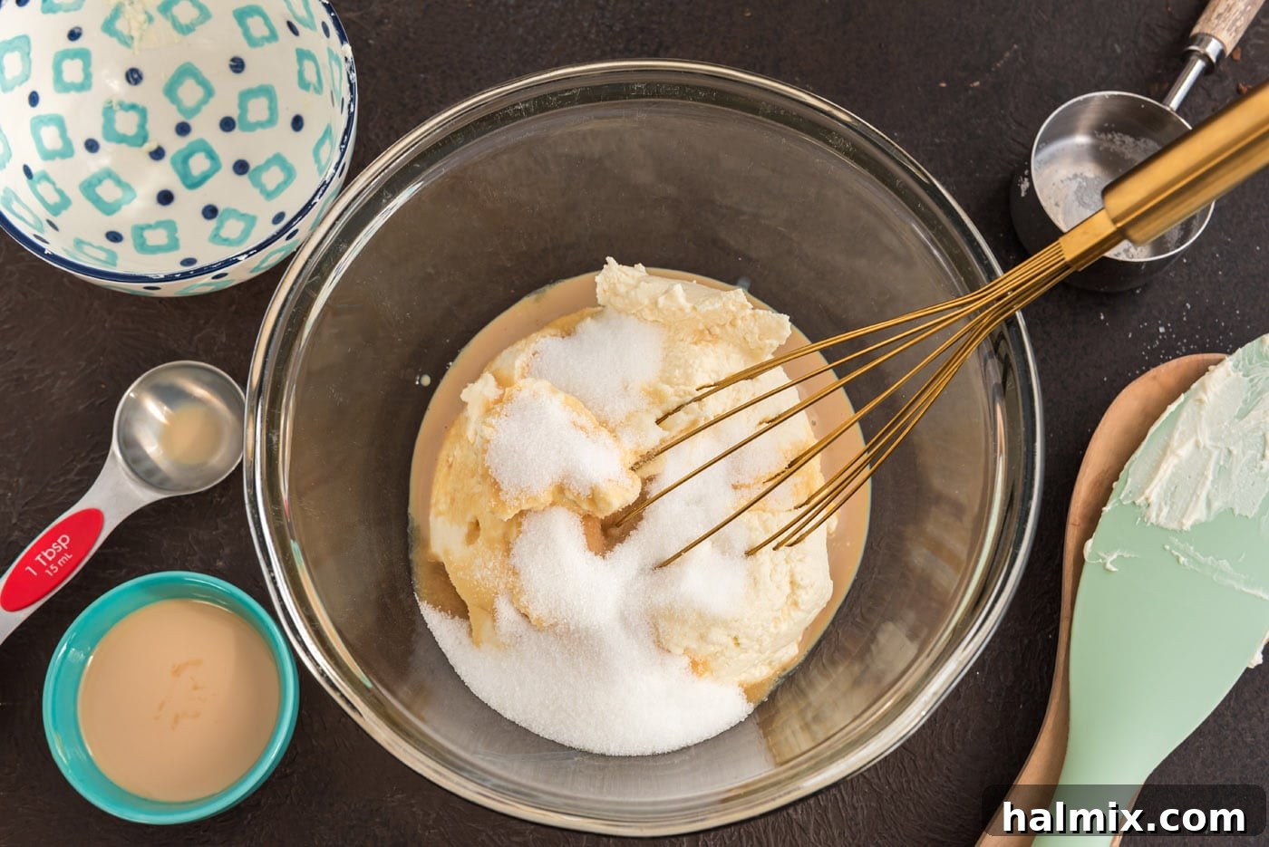 A close-up of a bowl where mascarpone cheese, sugar, and Bailey's Irish Cream are being gently whisked together.