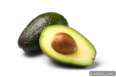 Fresh, ripe avocado halves showing creamy green flesh and a large pit.