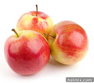 A stack of vibrant red apples, some whole, some sliced.