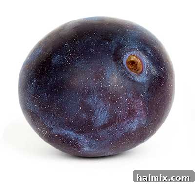 A close-up of dark purple plums with a few green leaves.