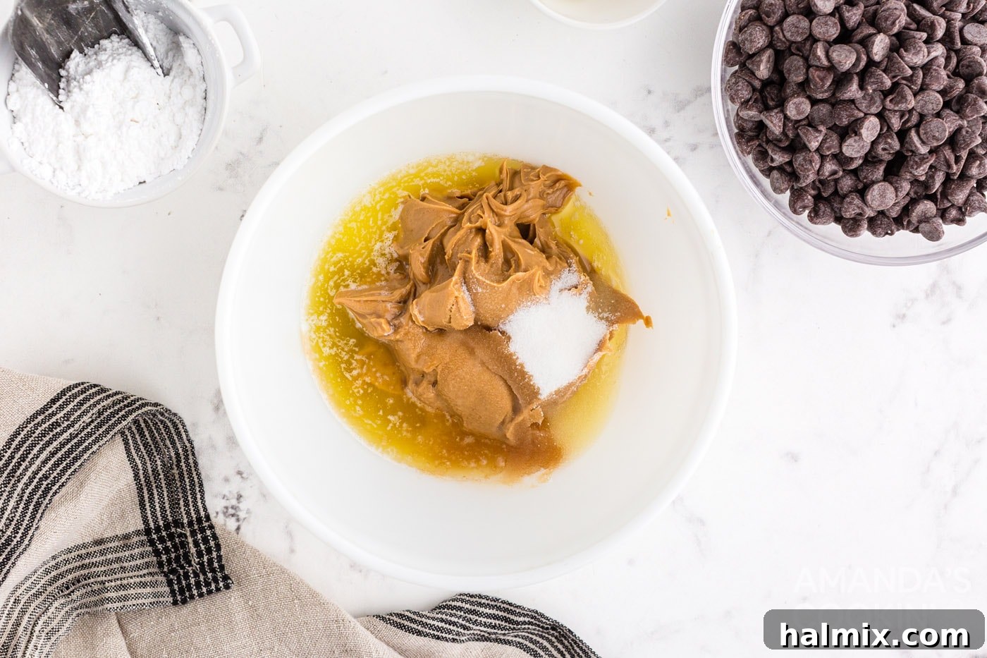 Melted butter, creamy peanut butter, granulated sugar, and vanilla extract being combined in a mixing bowl.