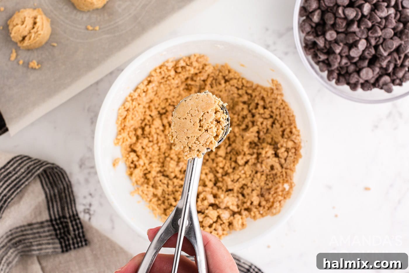 A cookie scoop portions out the peanut butter ball mixture onto a baking sheet.