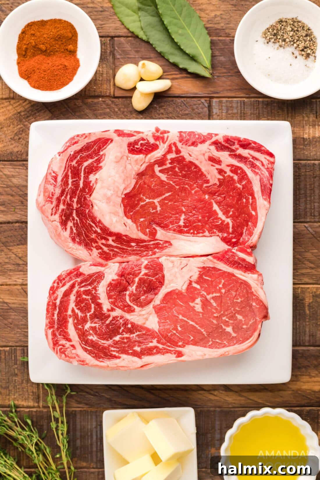 Assortment of fresh ingredients for making smoked ribeye, including spices, herbs, and butter.