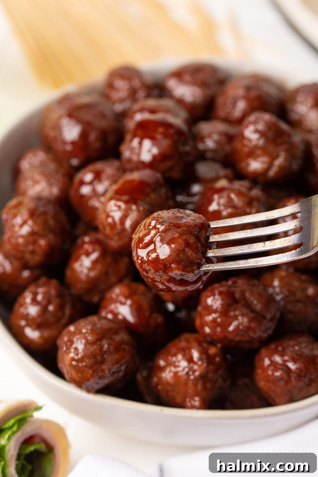 A large bowl filled with glistening grape jelly meatballs, ready to be served as a centerpiece appetizer at any gathering.