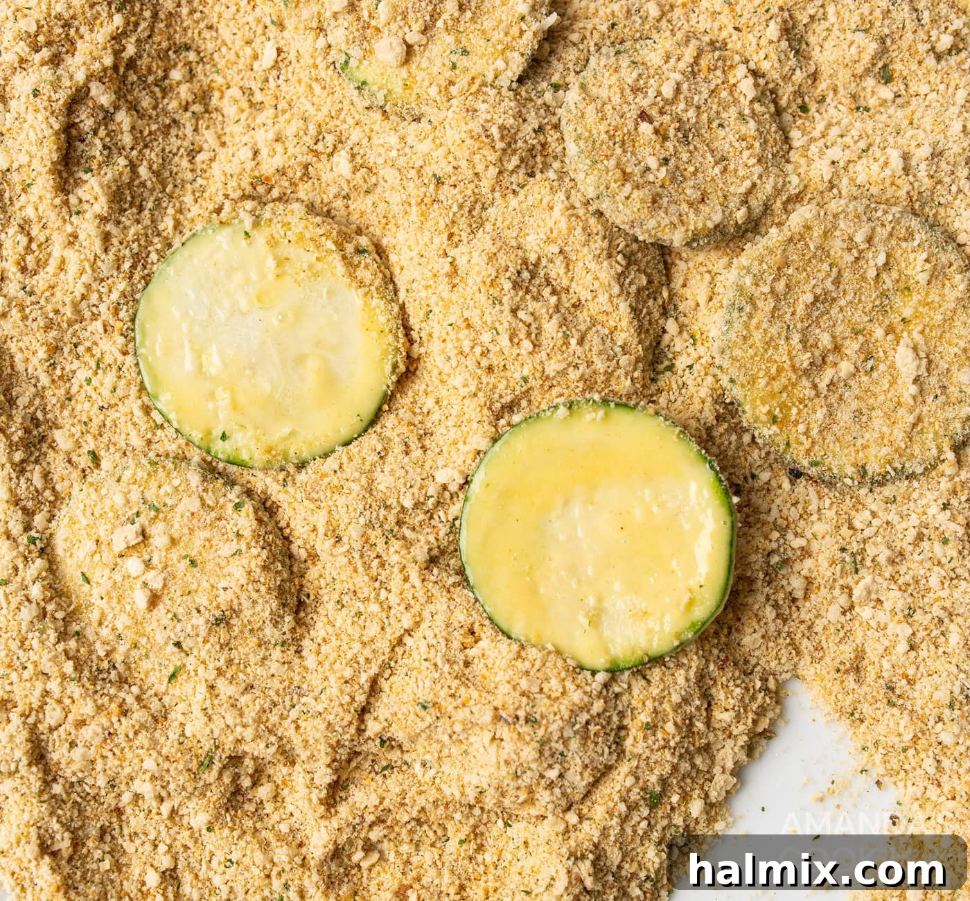 Dipping zucchini slices into a mixture of breadcrumbs and parmesan cheese