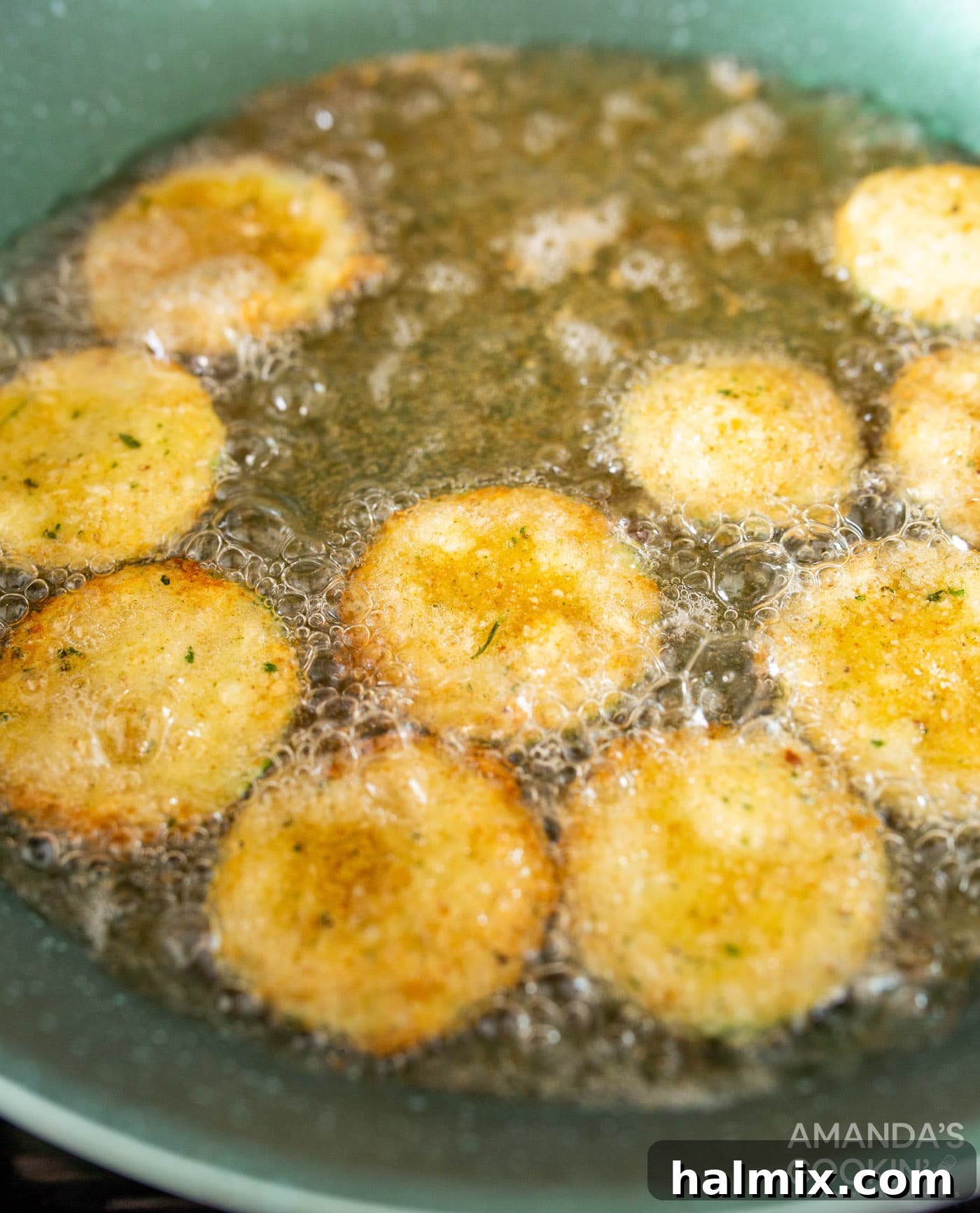 Fried zucchini cooking in hot oil within a skillet