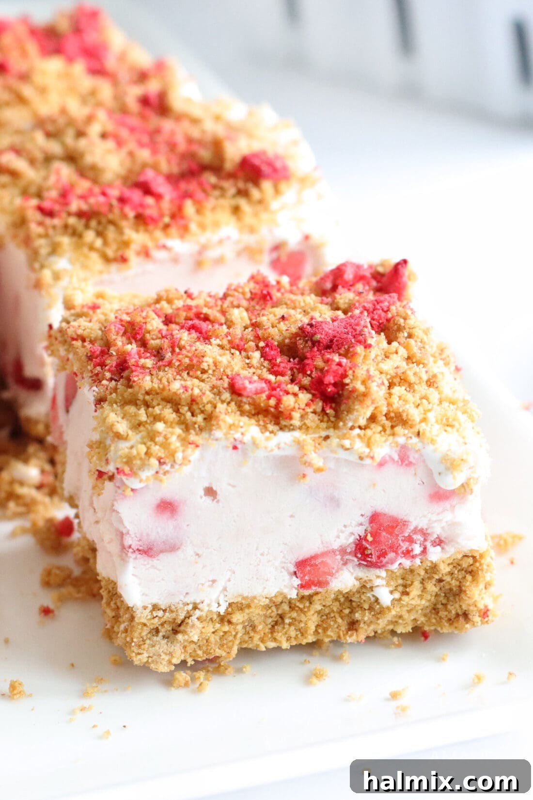 Slice of No Bake Strawberry Cheesecake Bars, showcasing creamy layers and graham cracker topping.