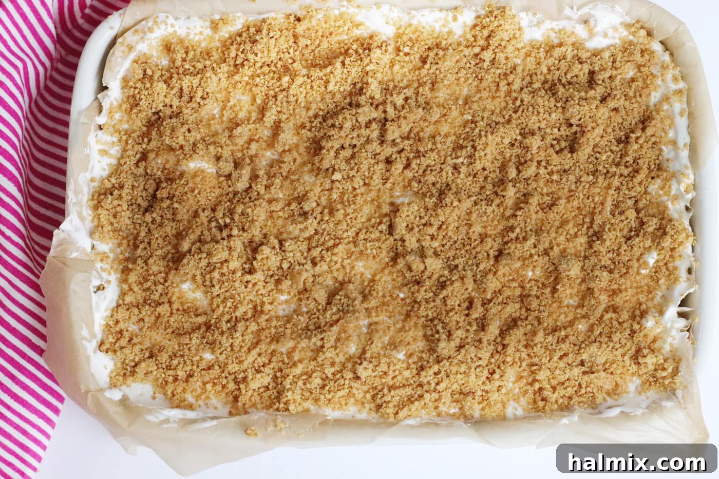 Graham cracker topping sprinkled over a layer of cool whip on the strawberry cheesecake bars.
