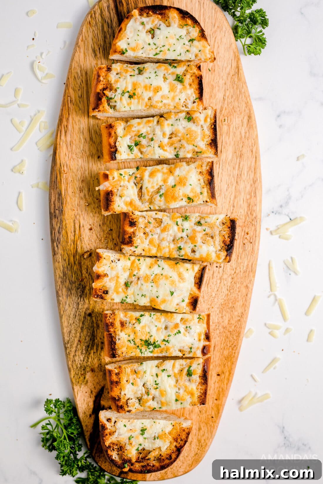 Slices of golden-brown Cheesy Garlic Bread arranged on a wooden cutting board, ready to serve