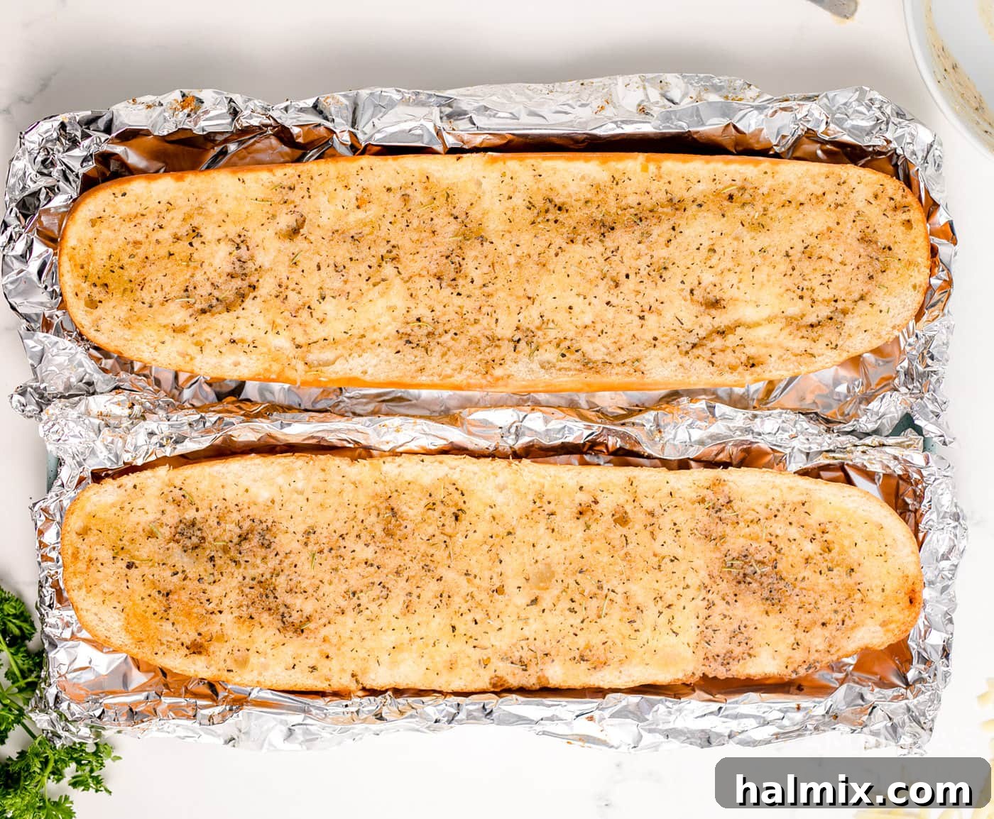 Lightly browned French bread halves after initial baking in foil